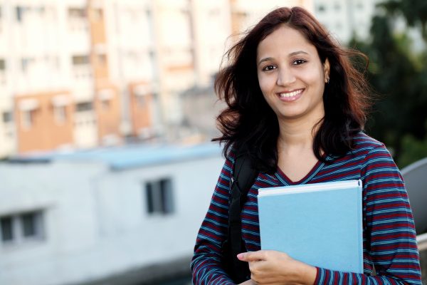 Cheerful young female college student at campus